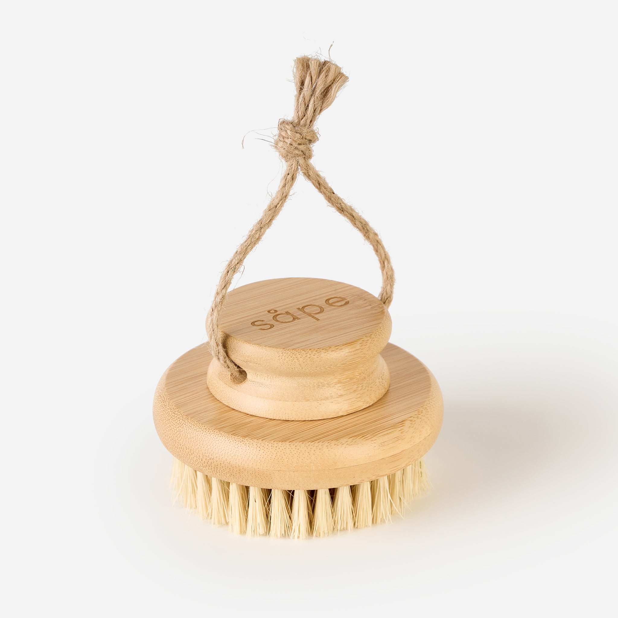 Angled view of Sisal Body Brush hanging by natural rope against a white background
