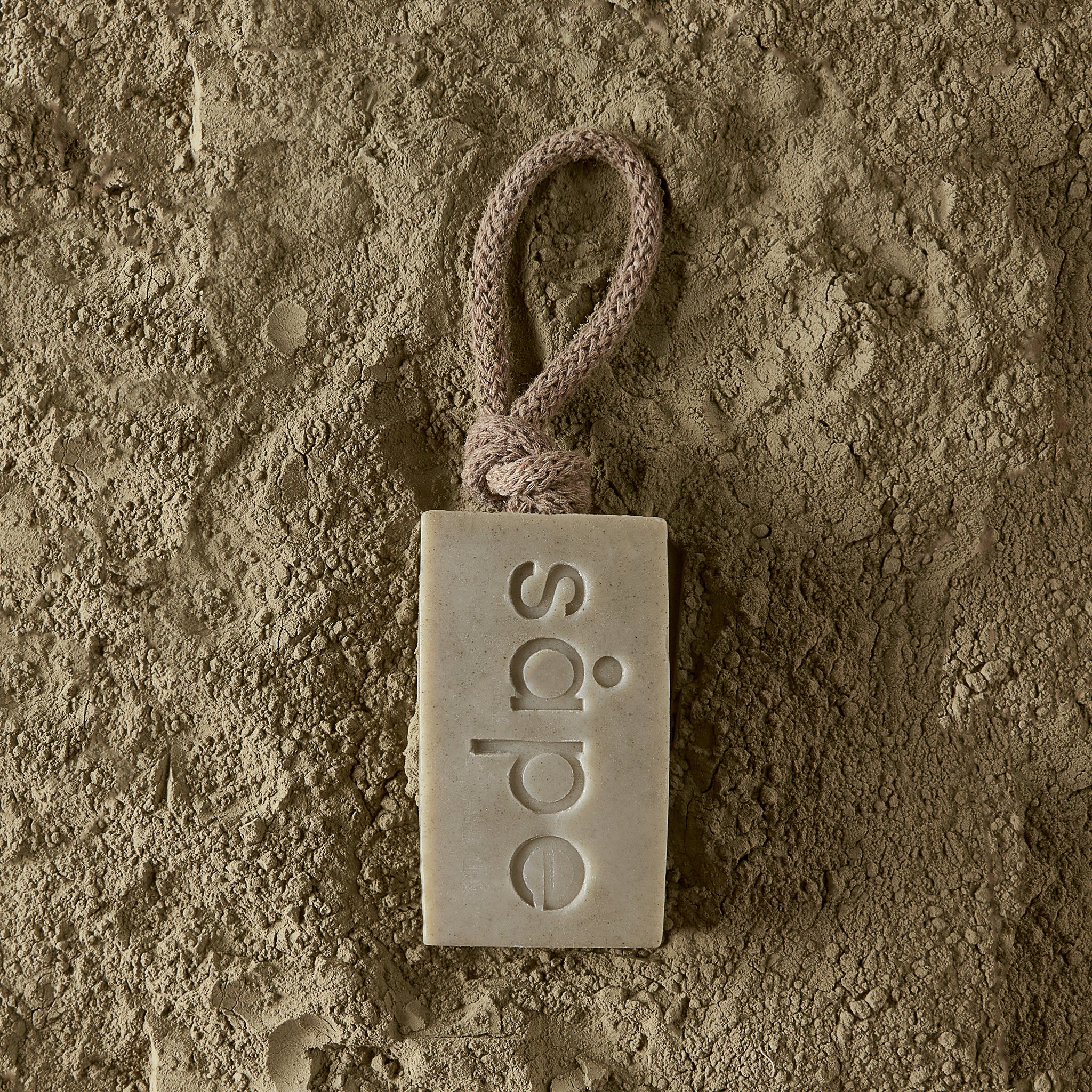 Bris soap on a rope laying on dead sea clay – plastic-free detox soap bar