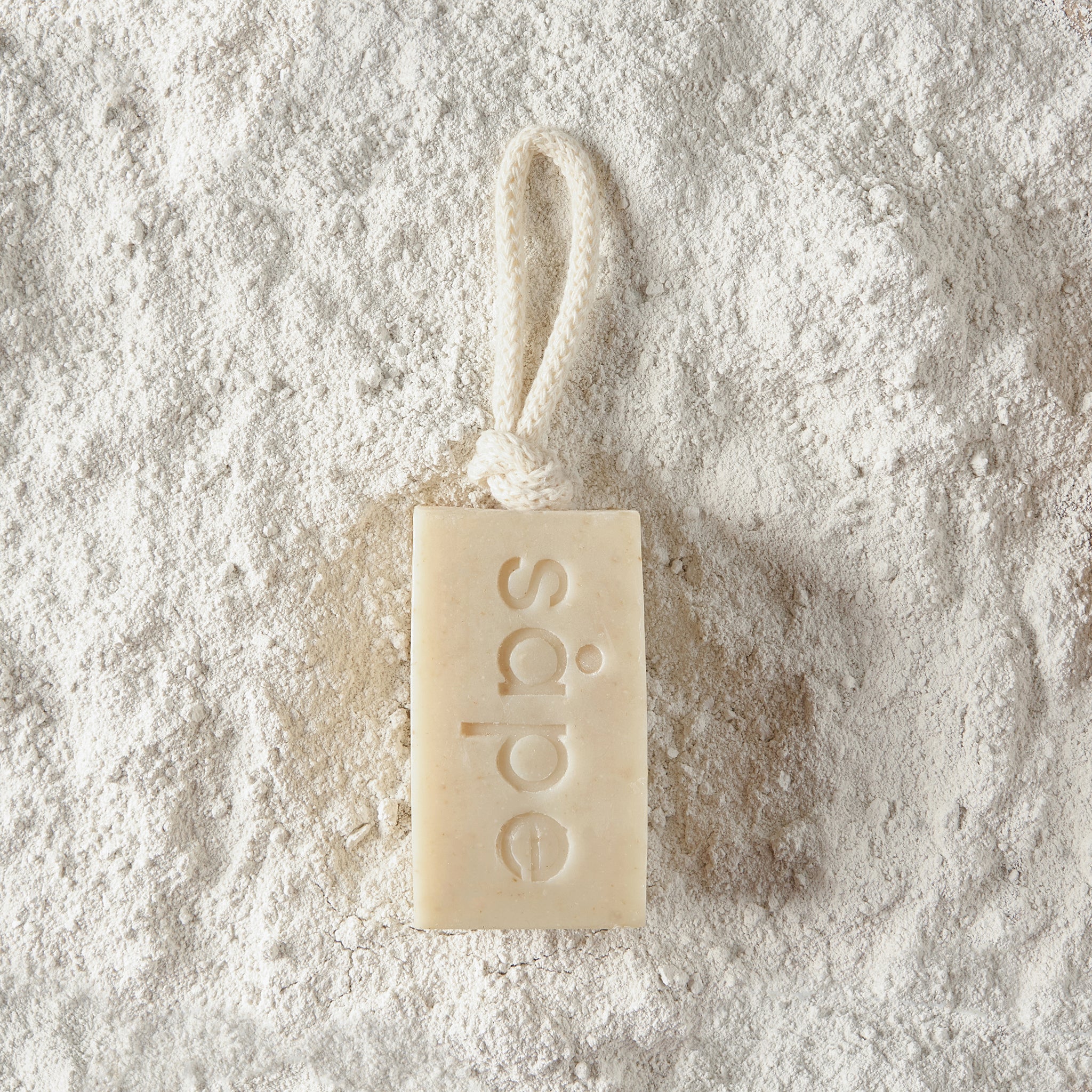 Havre oatmeal soap laying on white kaolin clay – cold-process floral soap on a rope