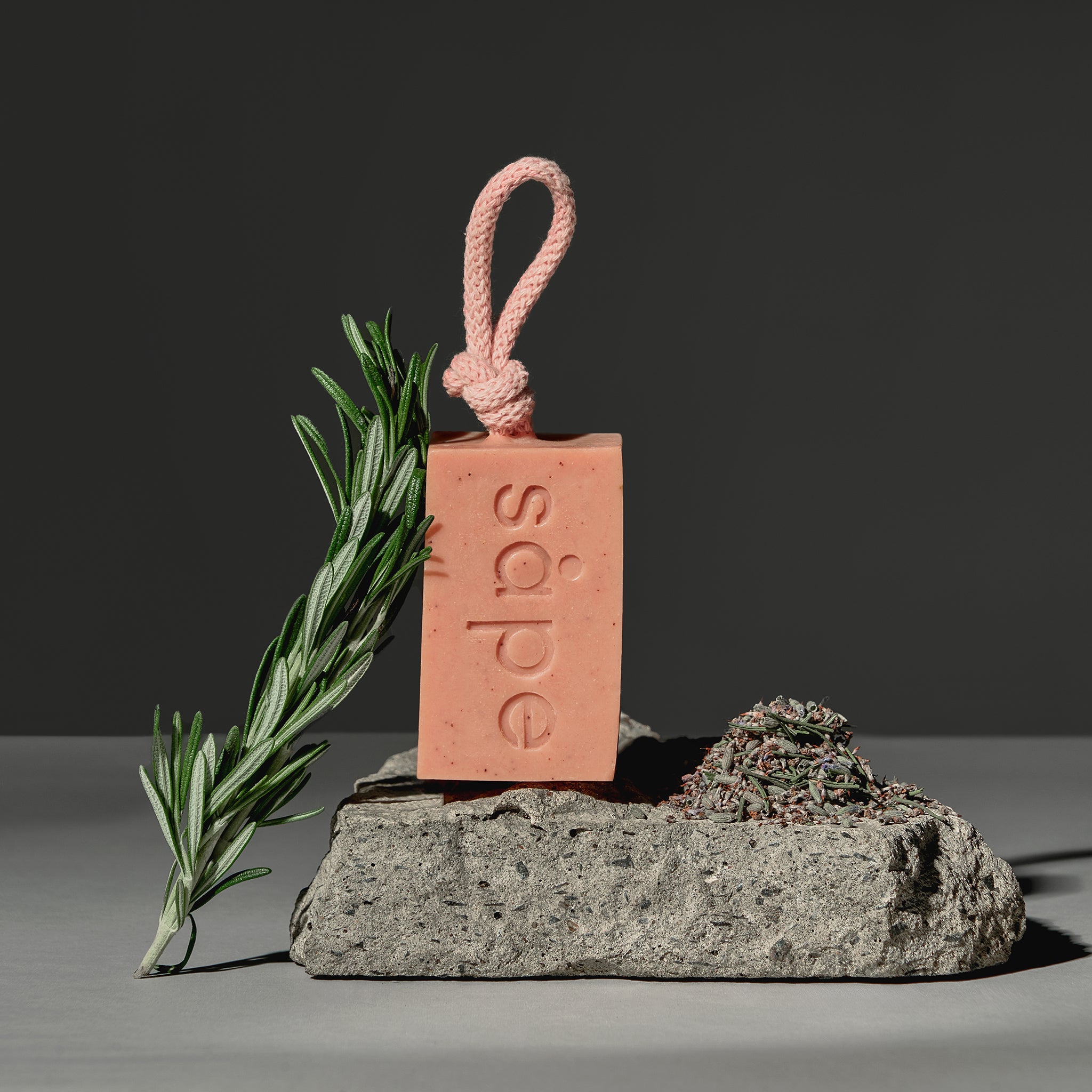 Pink Drom soap with rosemary sprig, displayed on stone with lavender